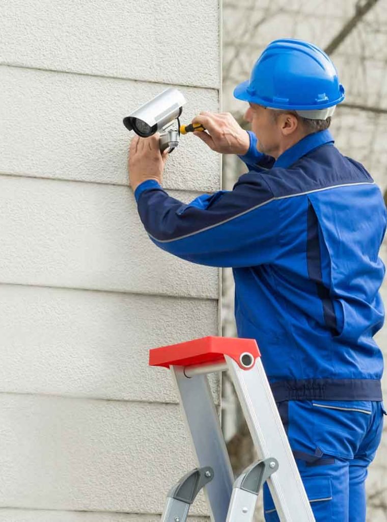 Male-Technician-Standing-On-Stepladder-Fitting-CCTV-Camera-1